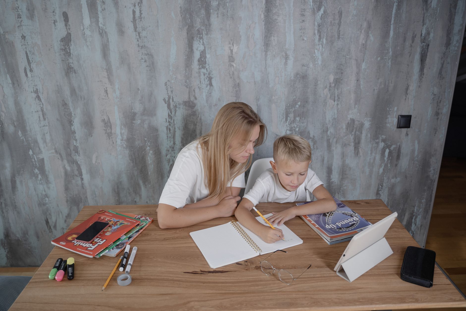 Parent helping child with homework on a tablet at a desk