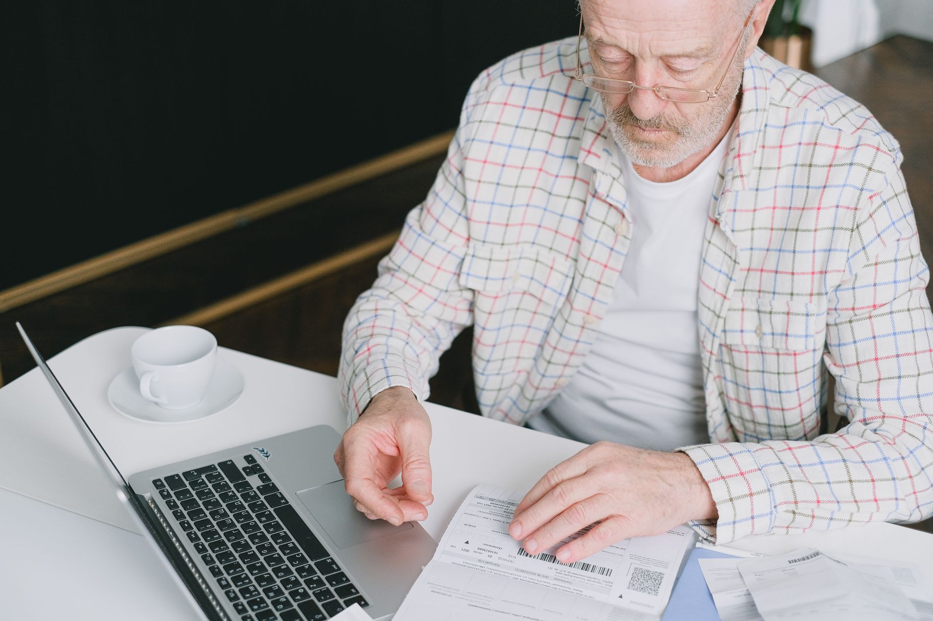 A person reviews a long document on a laptop at a clean desk.